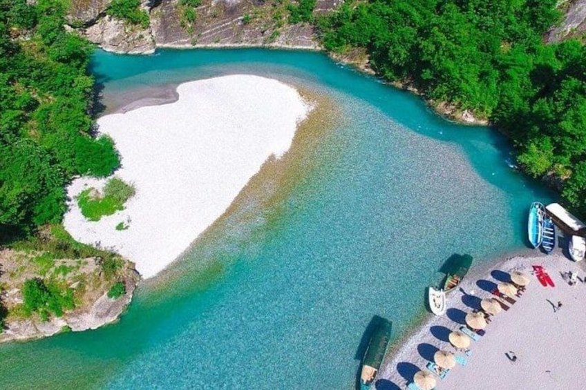 A beach with a white sand area, clear turquoise water, and a row of beach chairs and umbrellas. 1