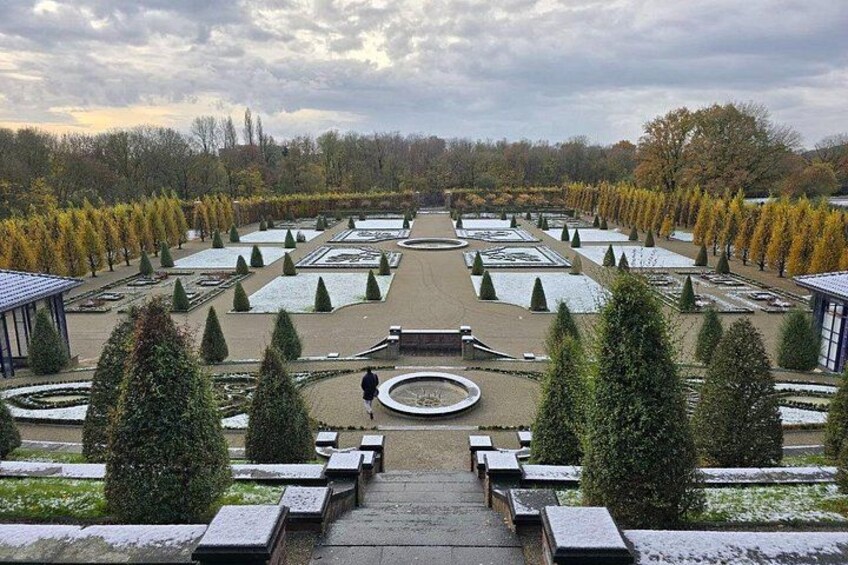 A formal garden with symmetrical pathways, neatly trimmed hedges, and a central circular feature. 5