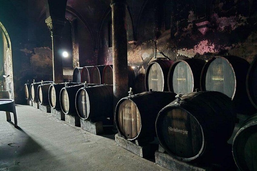 Wooden wine barrels in a dimly lit cellar with arched ceilings and stone walls. 1
