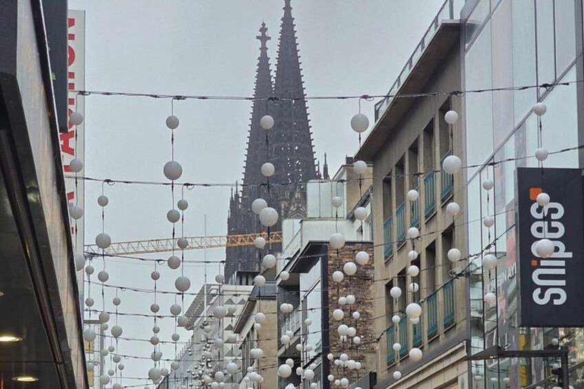 A street with hanging spherical lights, a building with a pointed spire, and a sign for 'snipes.' 2