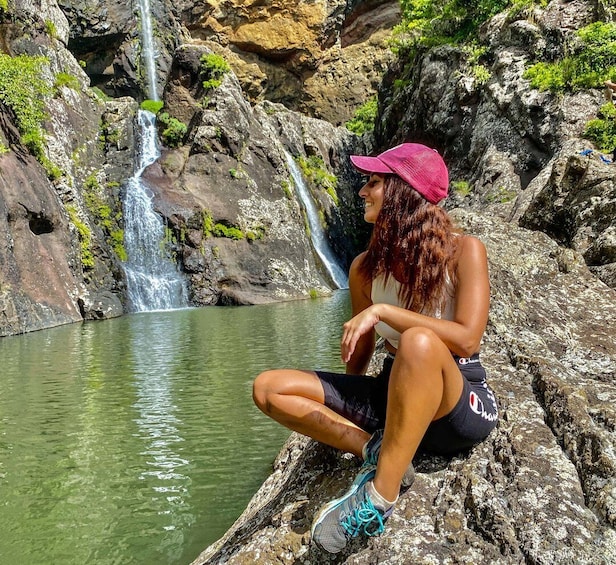 Una persona seduta su delle rocce vicino a una cascata. 1