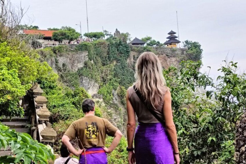 A man and a woman standing on a cliff overlooking a temple complex. 1