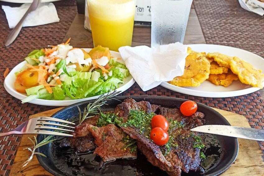 A meal with a steak, salad, and plantains on a table. 2