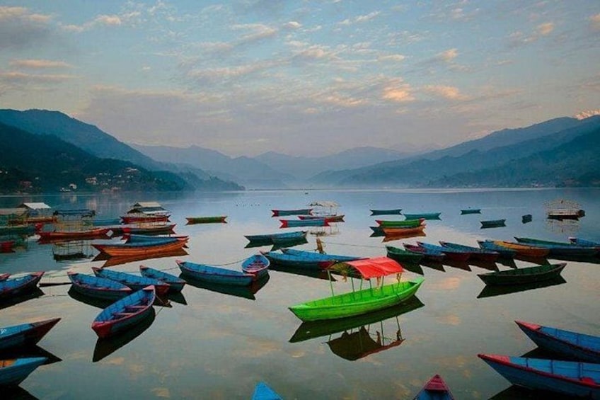 Un lac paisible où de nombreux bateaux aux couleurs vives sont amarrés, le tout étant entouré de montagnes. 3