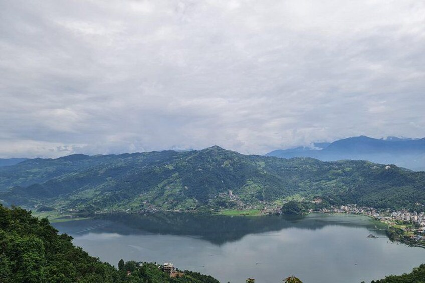 Un lac entouré de montagnes, une petite ville et un ciel nuageux. 4