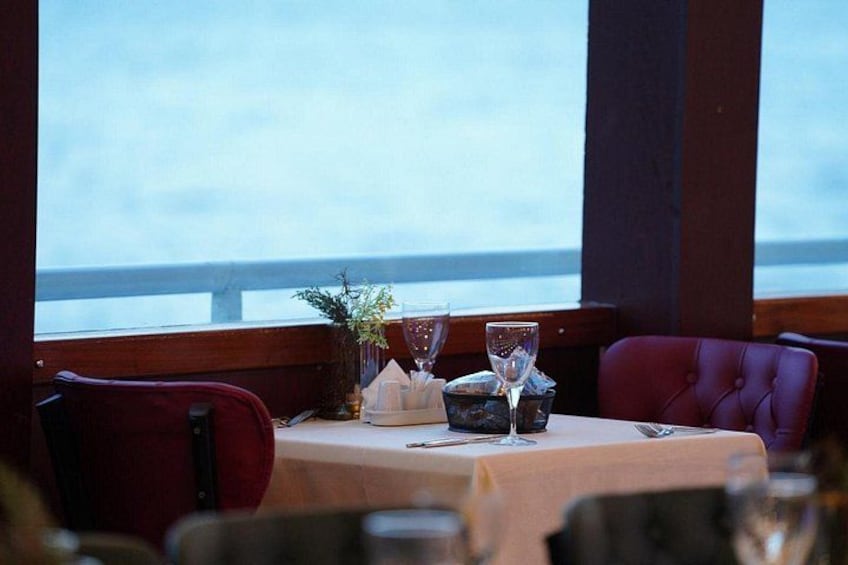 A dining table set with a vase, wine glasses, and a candle. 1