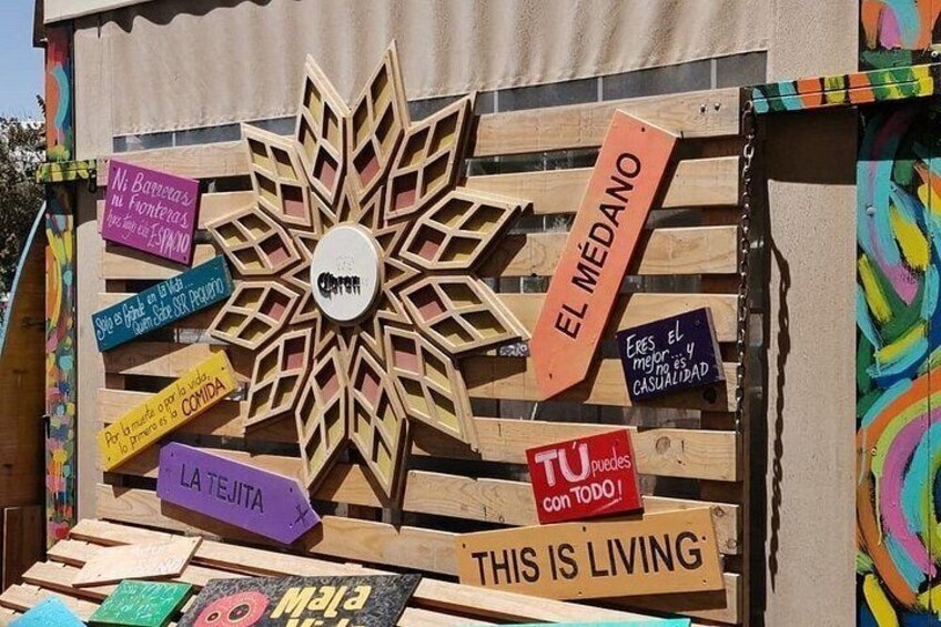 A wooden structure with colorful signs and a central flower-like design. 2