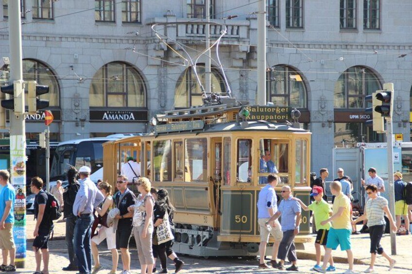 A tram with passengers, a street with shops, and a building with arched windows. 3