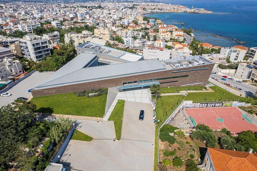 Un bâtiment moderne doté d’une conception architecturale originale, notamment au niveau du toit, et entouré d’un parc verdoyant et d’immeubles résidentiels. 5