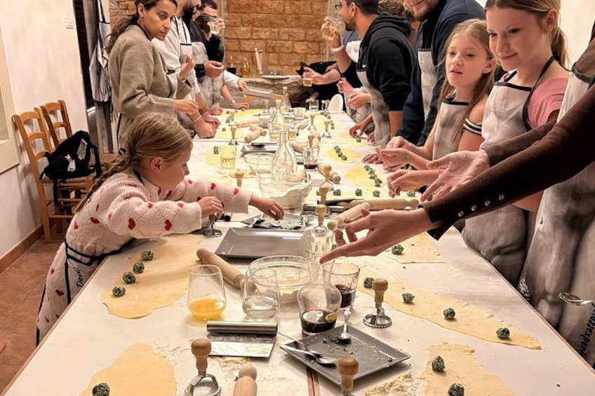 Eine Gruppe von Personen ist beim Kochen beschäftigt, Zutaten und Kochutensilien liegen auf einem Tisch verteilt. 5