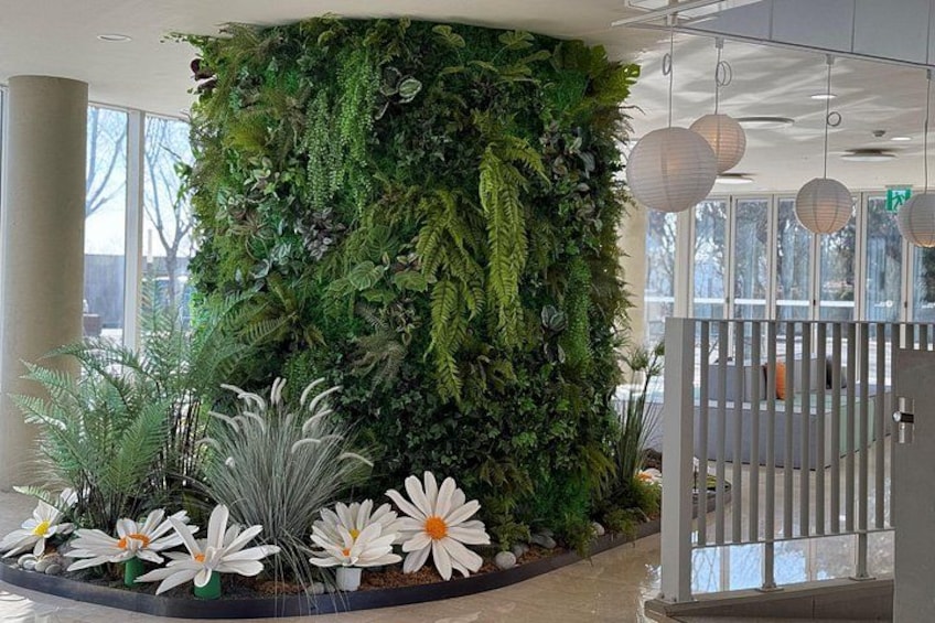 Eine vertikale Bepflanzung mit verschiedenen Pflanzen und Blumen, ein weißer Zaun und ein Tor. 3