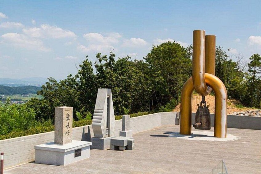 Ein Denkmal mit einer Glocke, einem Stein mit chinesischen Schriftzeichen und abstrakten Skulpturen. 5