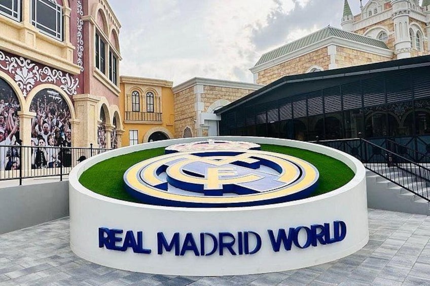 A circular plaza with a Real Madrid World logo, surrounded by classical architecture. 5