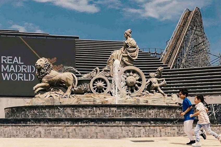 A sculpture with a lion, a woman, and a child. There's a billboard with 'REAL MADRID WORLD' text. 2