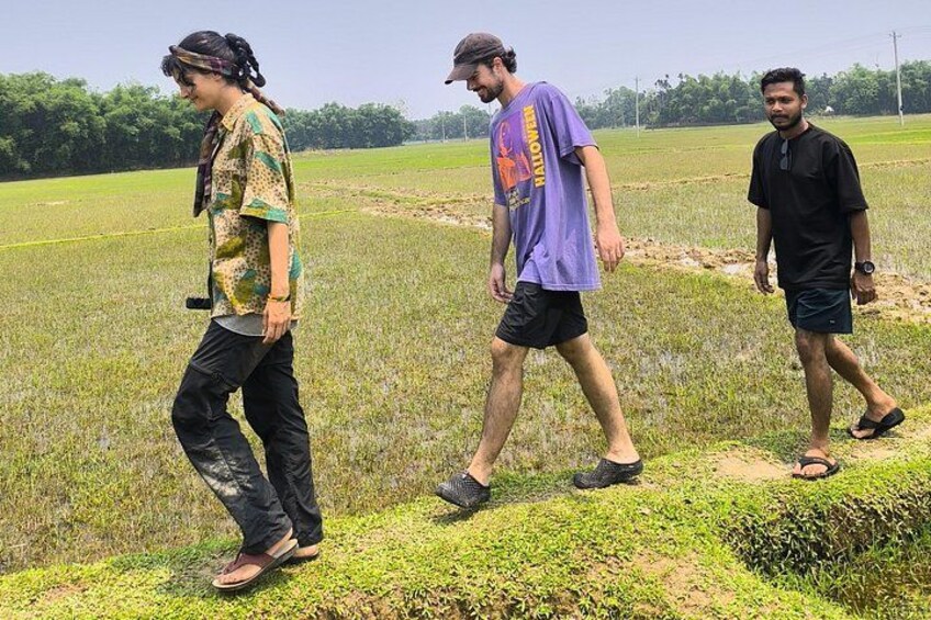 Three people walking in a field with a tractor in the background. 2