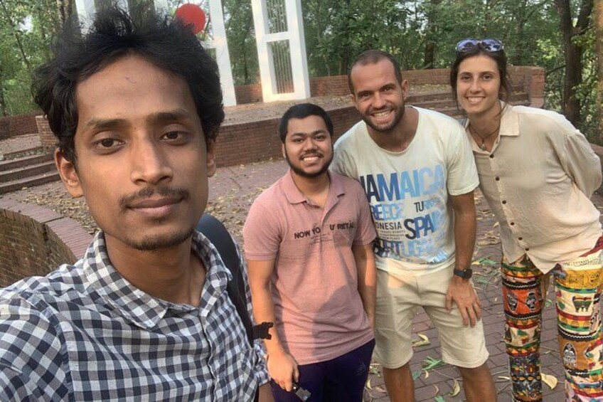A group of people outdoors, a brick wall, and a patterned pole. 4