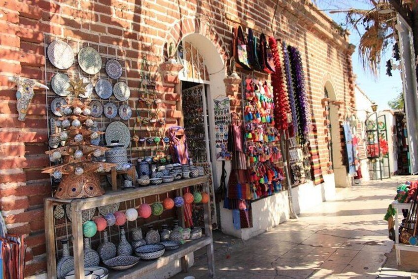 Un edificio de ladrillo con diversos artículos a la venta, entre ellos platos, cuencos y coloridos textiles. 2