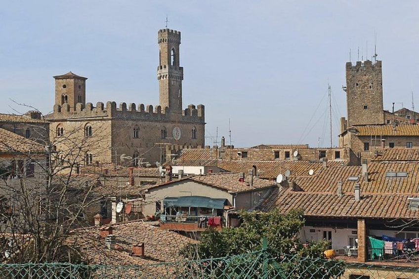 A historic building with a prominent tower, surrounded by traditional architecture and a cobblestone street. 3