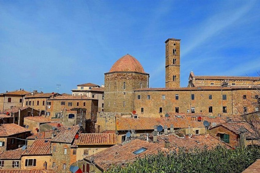 A historic town with a prominent dome and bell tower, surrounded by traditional buildings with terracotta roofs. 1