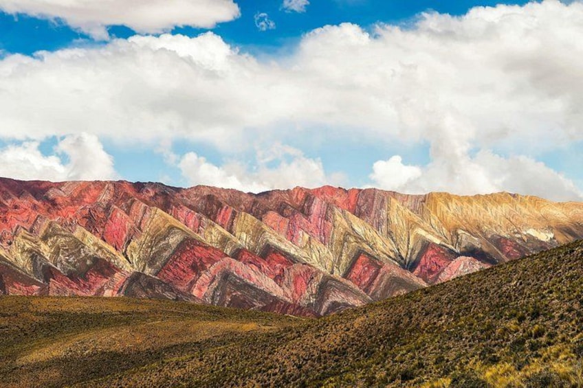 A mountainous landscape with layered rock formations in red, yellow, and white colors. 1