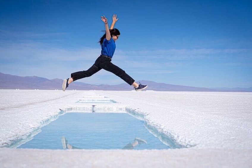A person jumping in a salt flat with a clear sky. 3