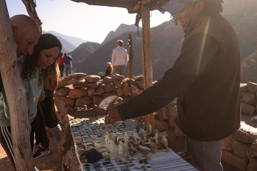 A person selling food at a market stall with mountains in the background. 5