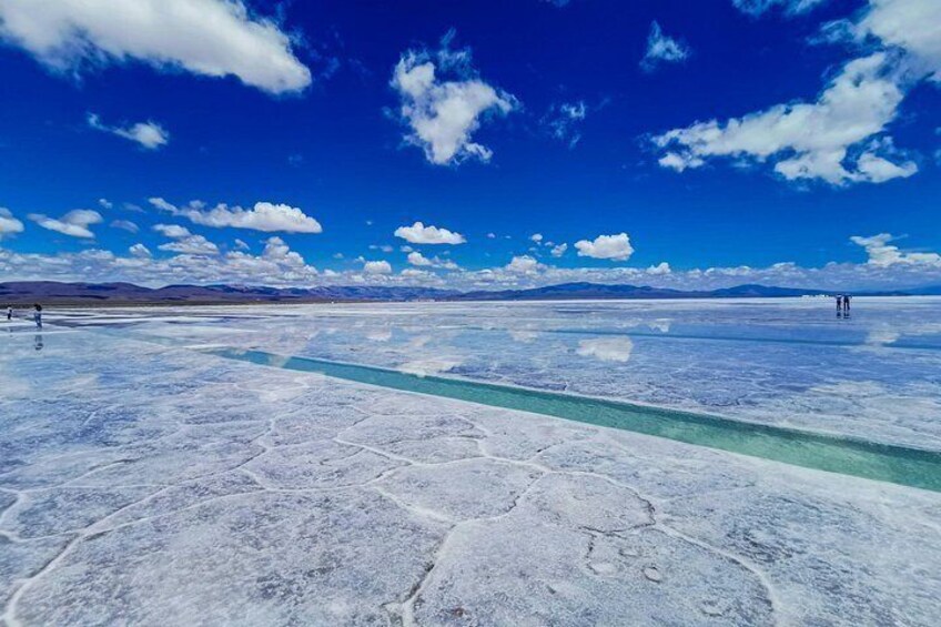 A vast salt flat with a clear blue sky and distant mountains. 4