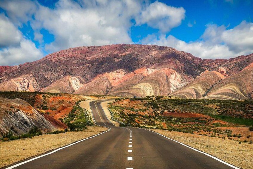 A winding road through a mountainous landscape with distinct geological formations. 2