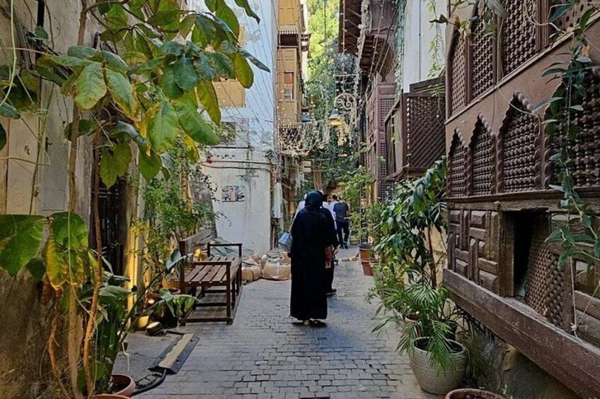 A narrow alley with potted plants, a wooden bench, and traditional architecture. 5