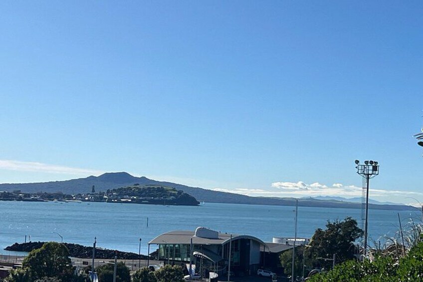 A coastal landscape with a clear sky, a body of water, a distant mountain, and a modern building. 5