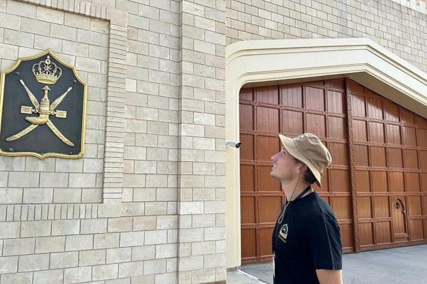Una persona parada frente a un edificio con un muro de ladrillo y un gran portón de madera. 5