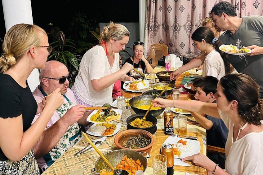 Un groupe de personnes est réuni autour d’une table, où se trouvent divers plats et boissons. 2