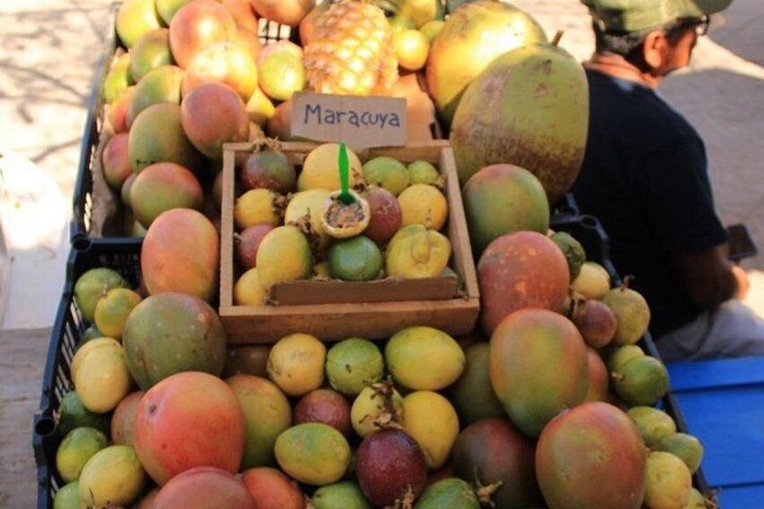 Un étal de fruits où l’on trouve différentes variétés de mangues, ainsi qu’une pancarte indiquant « Maracuya ». 5