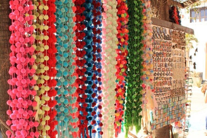 Colorful pom-poms hanging from a wall, a display of various items, and a ladder. 5