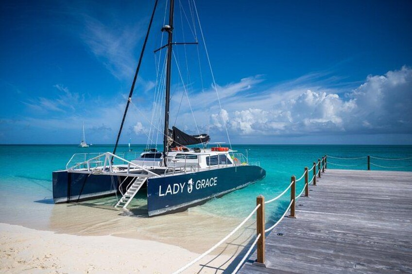 Yate Lady Grace atracado en un muelle, con agua turquesa cristalina y una playa arenosa al fondo. 1