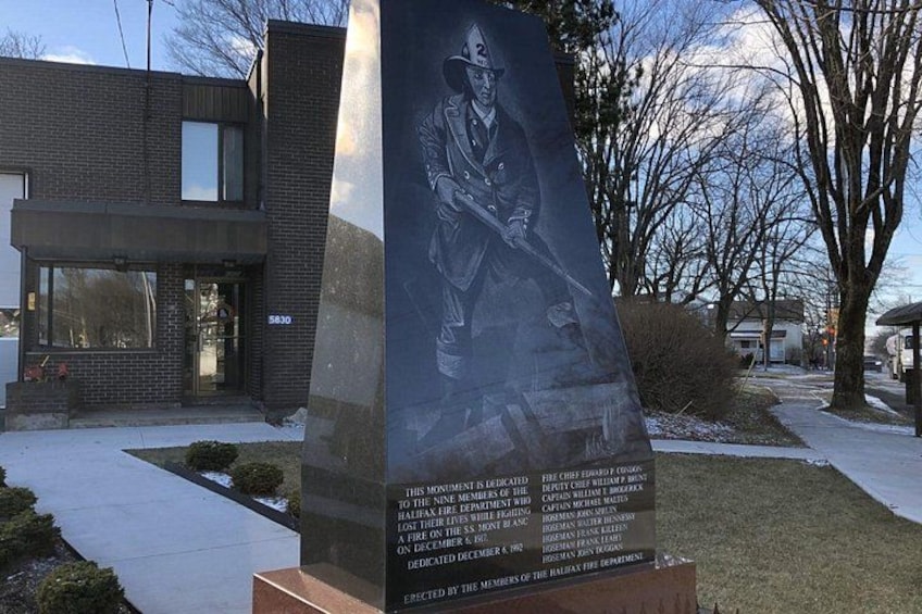 A memorial plaque with a firefighter's image and text, a modern building, and a tree-lined street. 5
