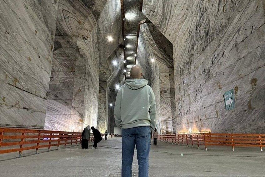 Een persoon loopt door een tunnel met marmeren wanden en een metalen hekwerk. 4