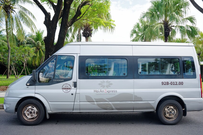 Valkoinen pakettiauto, jonka kylkeen on maalattu tekstit ”Hoi An Express” ja ”Expressions of Indochina”, on pysäköity kadulle, jonka taustalla näkyy palmuja. 5