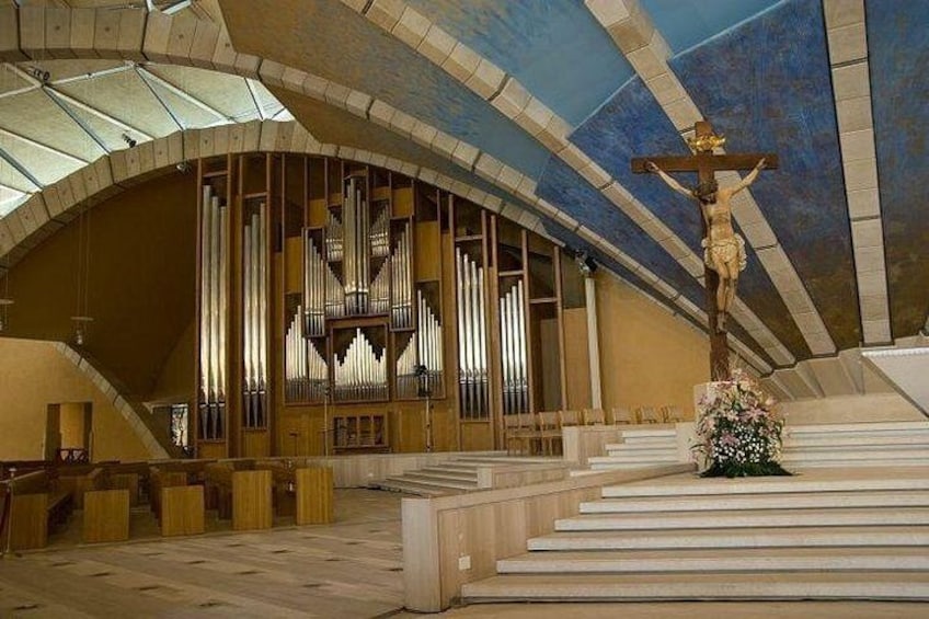 A church interior with a large organ, a crucifix, and a floral arrangement. 3