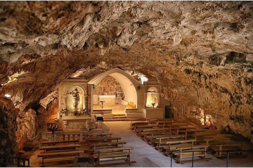 An underground church with stone benches and a central altar. 2