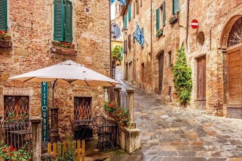 A narrow cobblestone street with a café, stone buildings, and a no entry sign. 1