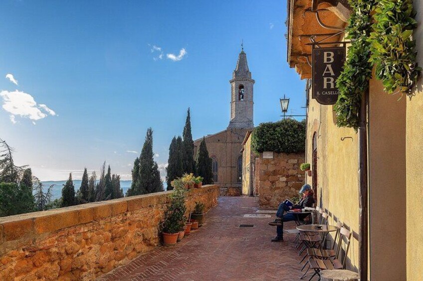 A terrace with potted plants, a stone wall, and a view of a church tower. 2