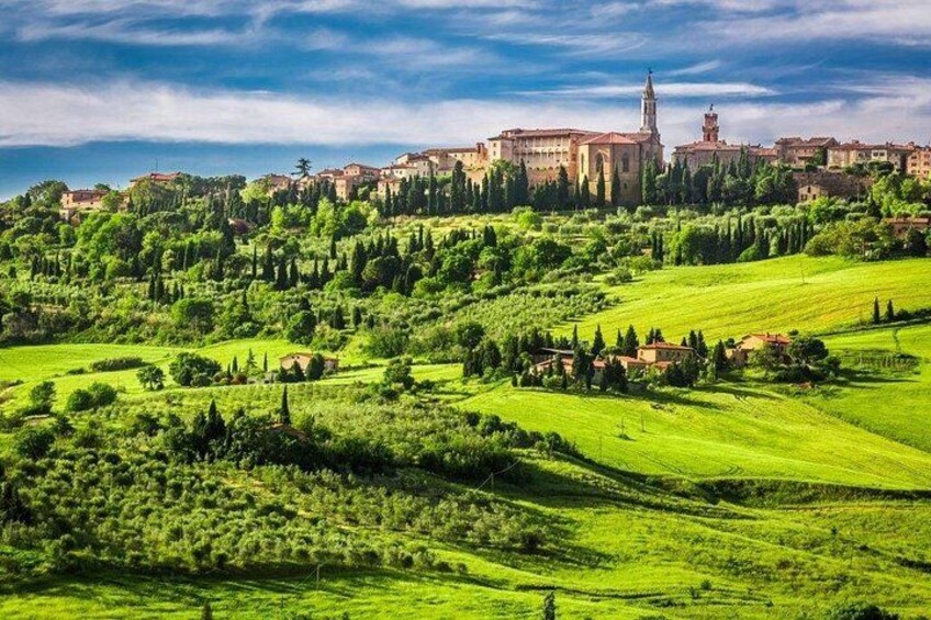 A lush green landscape with rolling hills, a prominent church with a tall bell tower, and a cluster of buildings in the background. 2
