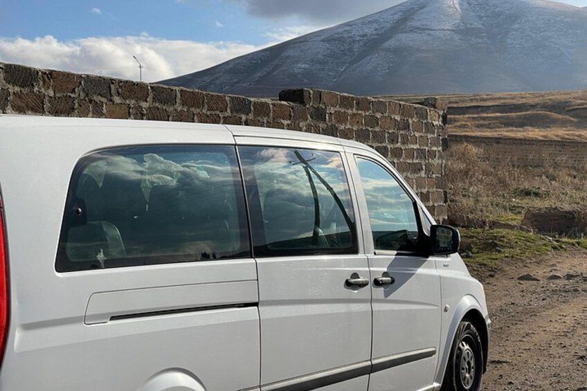 A white van parked by a brick wall with a mountain in the background. 2