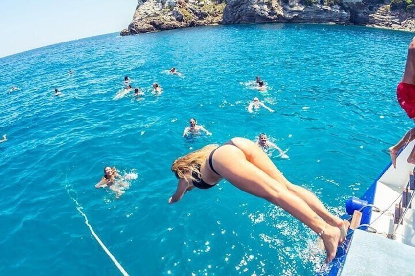A woman diving into clear blue water from a boat, surrounded by other swimmers. 5