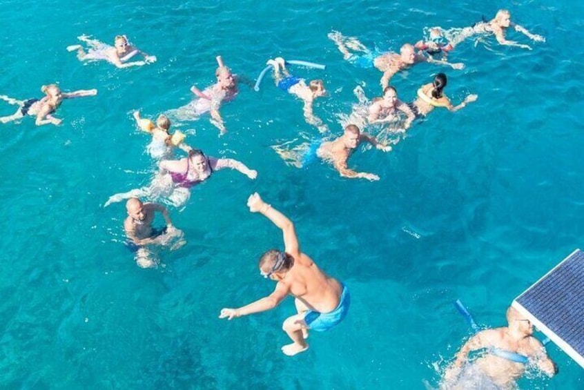 A group of people swimming in a clear blue pool. 1