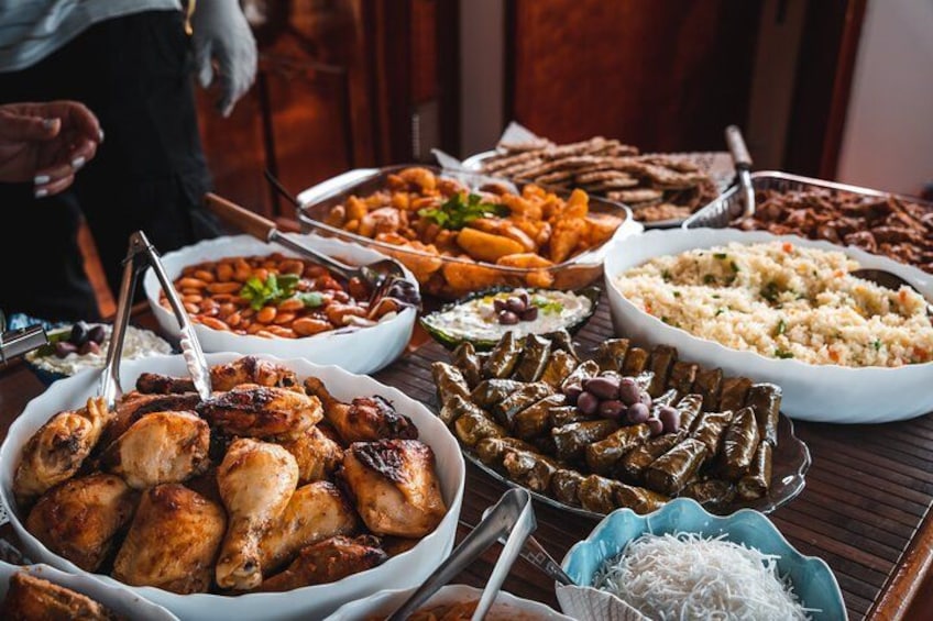 A table with various dishes including roasted chicken, stuffed grape leaves, and rice. 2