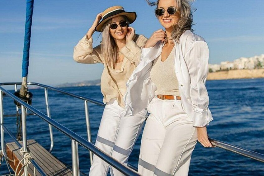 Two people on a boat with a clear blue sky and a coastline in the background. 3