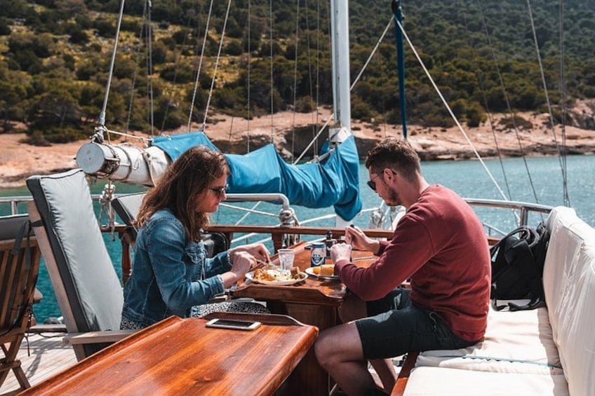 Two people dining on a boat with a scenic coastal background. 4