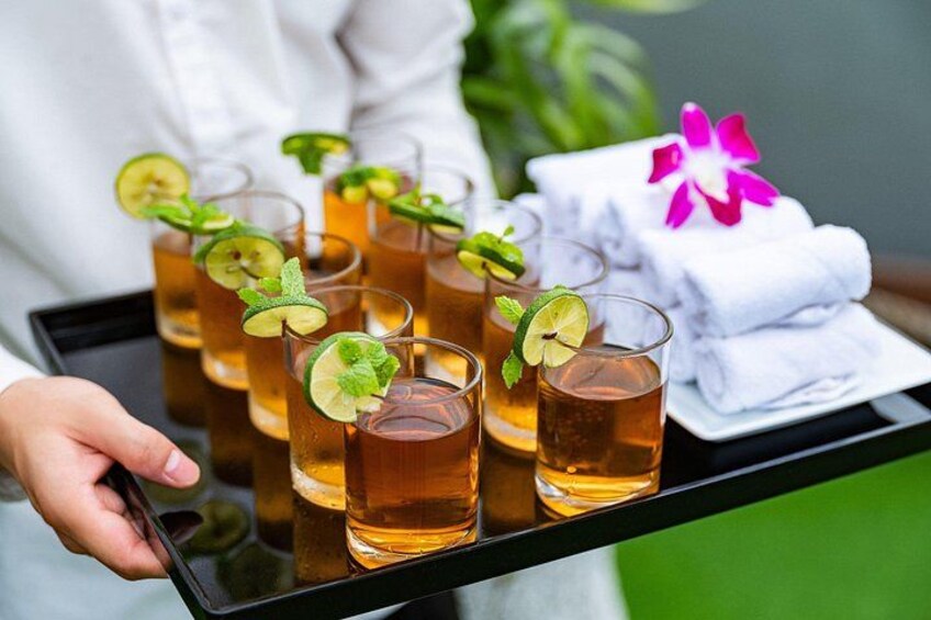 Una bandeja con vasos de una bebida adornada con lima y menta, sostenida por una persona. 3